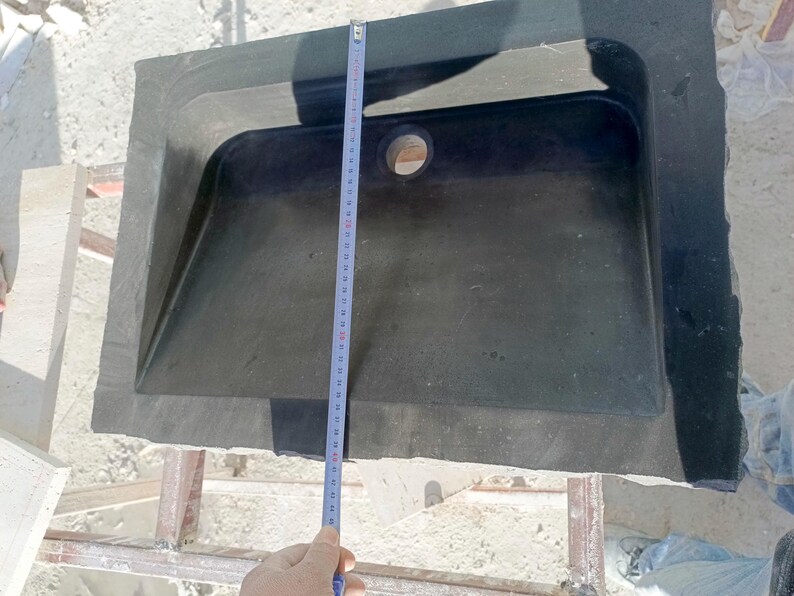 Pu&ograve; includere: Un lavandino rettangolare in pietra grigio scuro con un foro di scarico centrale. Un metro a nastro mostra la lunghezza del lavandino. Il lavandino ha una superficie leggermente strutturata e un bordo esterno rialzato. Il lavandino misura circa 76 cm di lunghezza.