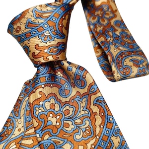 Può includere: Cravatta di seta con un motivo paisley dettagliato nei toni dell'oro, dell'arancione e dell'azzurro. La cravatta è annodata, mostrando l'intricato design e le variazioni di colore. L'estetica generale è classica ed elegante.