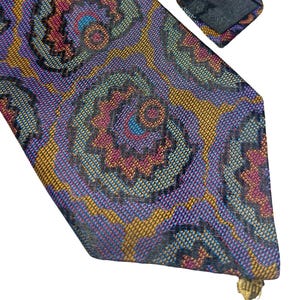 Puede incluir: Una corbata estampada con un diseño floral repetido en tonos morado, dorado, verde azulado y burdeos. La corbata está hecha de tela tejida y tiene un extremo puntiagudo. Un accesorio clásico.