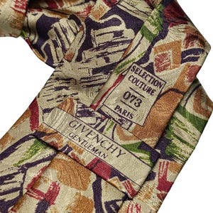 Puede incluir: Una corbata con un patrón abstracto en tonos morado, verde, rojo y beige. La parte posterior de la corbata muestra una etiqueta con el texto SELECTION COUTURE 073 PARIS y una segunda etiqueta con el texto GIVENCHY GENTLEMAN en tinta oscura.