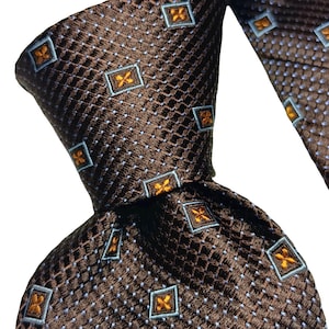 以下が含まれることがあります： 小さな正方形と青とオレンジの幾何学模様が繰り返される茶色のネクタイ。 ネクタイは結ばれており、生地の質感と詳細を示しています。