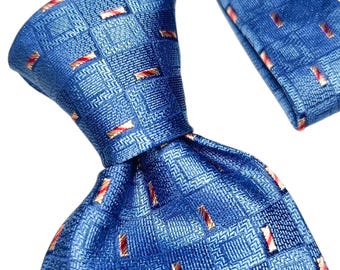 May include: A blue silk tie with a repeating pattern of small rectangles in red and gold. The tie is knotted, showing the front and back of the fabric. The background is white.