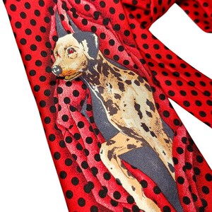以下が含まれることがあります： 黒い水玉模様の赤いネクタイと犬のイラスト。犬はベージュ、黒、グレーです。ネクタイは光沢のある素材で作られています。