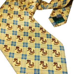 May include: A yellow silk tie with a repeating pattern of brown anchors and blue checkered squares. The tie is angled, showing the front and back, with a green tag visible.
