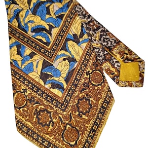 Puede incluir: Una corbata estampada con un diseño floral repetido en amarillo, azul y marrón. La corbata tiene un borde detallado con un patrón geométrico. La corbata está hecha de un material brillante.