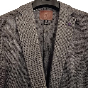 May include: A gray and black tweed blazer with a notched lapel and a small purple lapel pin. The blazer has a brown leather label that reads "SCOTCH & SODA AMERICAN FORTUNE". The size is XL/52.