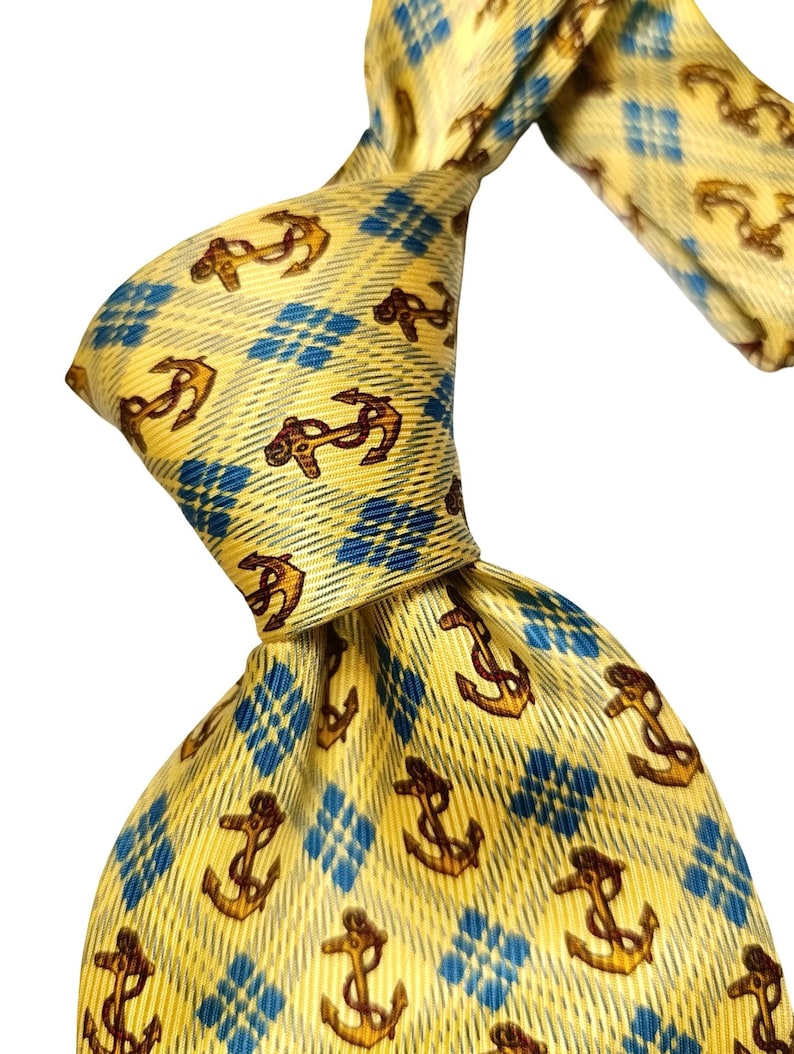 May include: Yellow necktie with a repeating pattern of brown anchors and blue diamond shapes. The tie is knotted, showcasing the fabric's texture and design. A classic accessory for formal or nautical-themed attire.