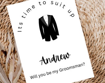 May include: A white card with black text that reads "It's time to suit up Andrew Will you be my Groomsman?"  A black and white illustration of a tuxedo is above the text.