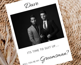 May include: A black and white photo of two men in suits. The text "Dave" is at the top of the card. The text "ITS TIME TO SUIT UP.... WILL YOU BE MY GROOMSMAN?" is at the bottom of the card.