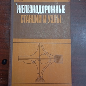 Op de afbeelding: Een vintage boek met een bruine en beige kaft. De titel, in het Russisch, luidt "Spoorwegstations en knooppunten". De kaft toont een diagram van een spoorwegknooppunt. Het boek heeft een versleten uiterlijk, wat duidt op leeftijd en gebruik.