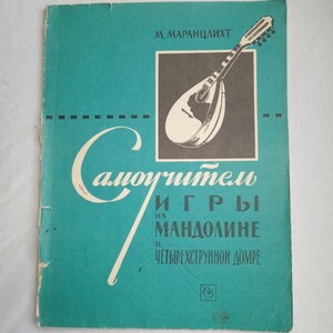 Puede incluir: Una portada de libro vintage de color turquesa con el título "Самоучитель игры на мандолине и четырехструнной домре" y una ilustración en blanco y negro de una mandolina. El nombre del autor, M. Marantslikht, está en la parte superior.