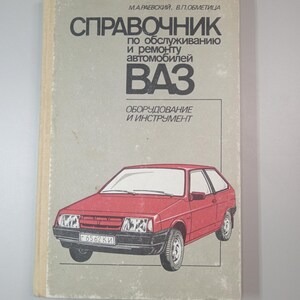 May include: A vintage book with a red car illustration on the cover. The book's title is in Russian, with the word "VAZ" prominently displayed. The cover also includes the text "Equipment and Tools."