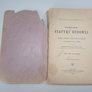 May include: An open, aged book with a light brown cover and a detached, torn cover on the left. The book's title, "STATYKI BUDOWLI," is visible, along with other Polish text. The book is from Lwow, 1902.