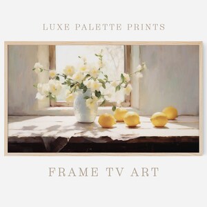 May include: A framed art print featuring a still life scene. A white vase holds white flowers, with lemons scattered on a table. The text "LUXE PALETTE PRINTS" and "FRAME TV ART" are visible.