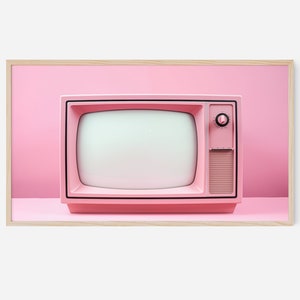以下が含まれることがあります： ピンクのビンテージテレビ。黒い画面と右側に丸いノブがあります。テレビはピンクの表面の上に置かれています。