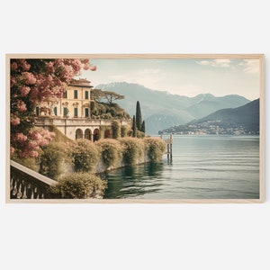 Peut inclure: Une villa jaune avec un balcon donnant sur un lac avec des montagnes en arrière-plan. La villa est entourée d'une végétation luxuriante et de fleurs roses.