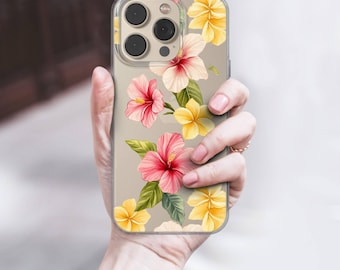 Puede incluir: Funda transparente para teléfono con un diseño floral de flores de hibisco rosas y amarillas y hojas verdes. La funda tiene un borde transparente y se sostiene en una mano.