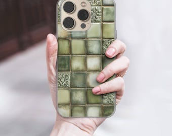 May include: A clear phone case with a green tile design. The case has a square pattern with varying shades of green and embossed floral accents. The phone case is held in a person's hand.