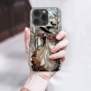 May include: A clear phone case featuring a witch illustration in a forest scene. The design includes a witch in a black hat and flowing dress, with autumn leaves and bats. The case has a glossy finish.