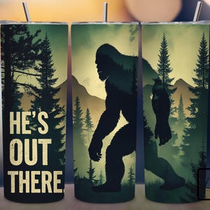May include: A set of three stainless steel tumblers with a forest scene and the text "He's Out There". The scene features a silhouette of Bigfoot walking through the trees.