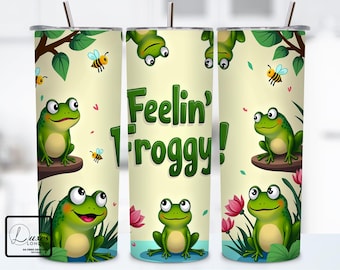 May include: A set of three green and white stainless steel tumblers with a frog and bee design. The tumblers feature the text "Feelin' Froggy!"