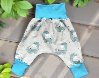 Op de afbeelding: Babybroek met een lichtgrijze achtergrond en een patroon van teal dinosaurussen. De broek heeft een hoge, lichtblauwe tailleband en bijpassende manchetten. Kleine rode stippen zijn over het ontwerp verspreid.