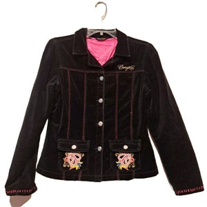 May include: Black corduroy jacket with red stitching and decorative embroidery on the pockets. The jacket has a button-up front, two front pockets, and the word "Coogi" embroidered on the chest.