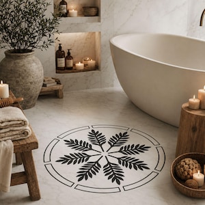 May include: A circular floor decal featuring a black botanical fern leaf pattern arranged in a radial design, enclosed within a thin black circular border, applied to a white marble bathroom floor surface near a white freestanding bathtub.