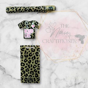 May include: A set of three gold and black leopard print accessories for nurses. The set includes a pen, a badge holder, and a scrub top charm. The charm has the text "Scrub Life" on it.