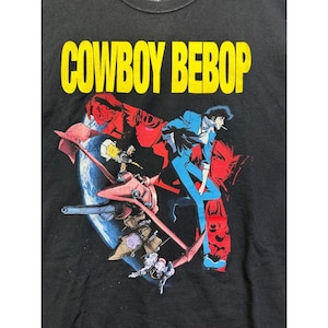 May include: Black t-shirt featuring the text "COWBOY BEBOP" in yellow. The graphic includes a character in a blue suit, a spaceship, and other characters in red and white against a backdrop of a planet.