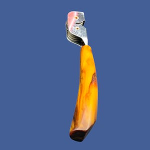 May include: A silver cigar cutter with a wooden handle. The handle is a dark brown color with streaks of orange and yellow.