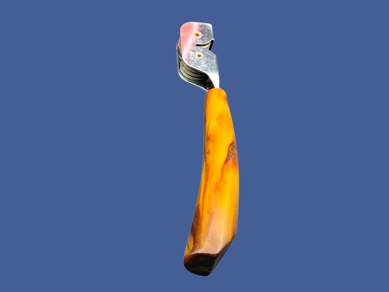 May include: A silver cigar cutter with a wooden handle. The handle is a dark brown color with streaks of orange and yellow.