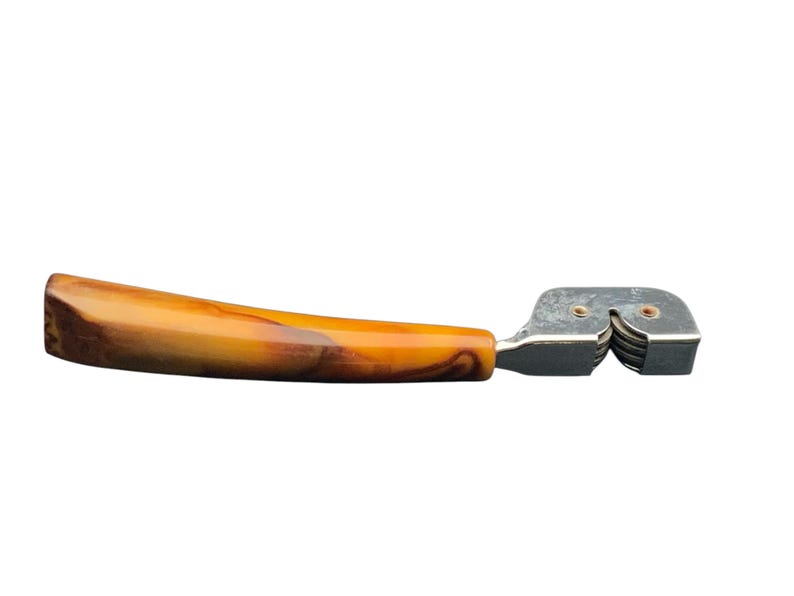 May include: A vintage knife sharpener with a brown and yellow marbled plastic handle and a silver metal sharpening mechanism.