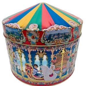 May include: A carousel-themed tin box with a colorful striped top and a detailed carousel scene around the sides. The box features a red base and gold accents, with illustrations of horses, swans, and children.