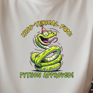 Könnte beinhalten: Weißes T-Shirt mit einem Cartoon-Schlangen-Design. Die Schlange ist grün mit gelben Punkten, trägt eine Partyhütchen und hat die Zunge draußen. Auf dem T-Shirt steht "HISS-TERICAL FUN" und "PYTHON APPROVED!"