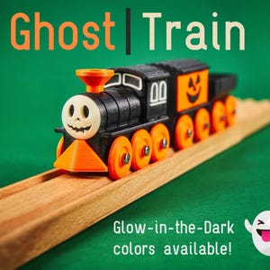 May include: A black and orange toy train with a ghost face on the front. The train is on a wooden track and has glow-in-the-dark colors available.
