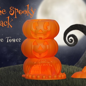 May include: A three-tiered orange pumpkin dice tower with the text "The Spooky Stack Dice Tower" on the background. The tower is made of three stacked pumpkins with carved faces. The bottom pumpkin has an open mouth and a small opening for dice to roll out.