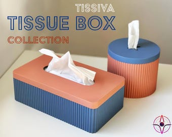 Könnte beinhalten: Zwei Taschentuchboxen, eine rechteckige und eine runde, beide in einem blau-orangen Farbschema. Die Boxen haben eine gerippte Textur und sind Teil der "TISSIVA TISSUE BOX COLLECTION".