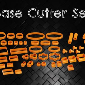 Puede incluir: Un juego de cortadores de galletas de plástico naranja en varias formas, incluyendo círculos, cuadrados, rectángulos y estrellas. El juego está etiquetado como "Base Cutter Set".
