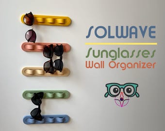 May include: A set of four colorful wall organizers for sunglasses. Each organizer is made of a flexible material and has a wavy design. The organizers are mounted on a white wall. The text "SOLWAVE sunglasses Wall Organizer" is visible in the image.