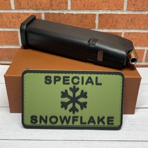May include: A green and black patch with the text "SPECIAL SNOWFLAKE" and a snowflake graphic.