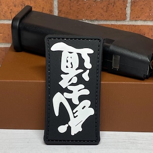 May include: Black patch with white Japanese characters that read "Black Dragon" on a brown surface.