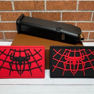 May include: Two black and red embroidered patches with a spider web and spider design. The spider web is red on the black patch and black on the red patch.
