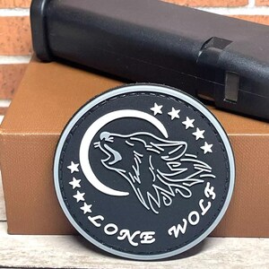 May include: Black and white embroidered patch with a wolf howling at the moon. The patch has five stars and the text "Lone Wolf" around the edge.