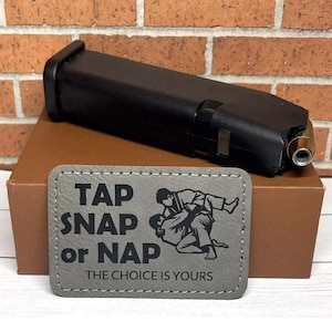 May include: A gray patch with the text "Tap Snap or Nap The Choice Is Yours" and a black and white illustration of two people in a martial arts pose.
