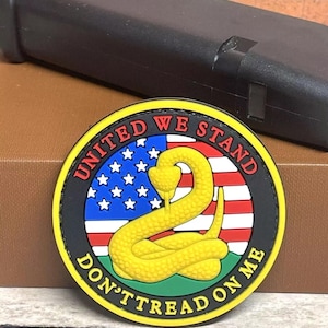 May include: A yellow, black, red, white, and green embroidered patch with a snake and the text "United We Stand Don't Tread On Me".
