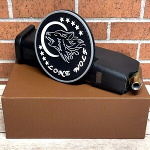 May include: A black and white patch with a wolf howling at the moon. The patch has a white border with stars and the text "Lone Wolf" around the edge.