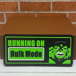 May include: Green and black patch with the text "RUNNING ON HULK MODE" and a cartoon image of the Hulk with a green face and a black outline.