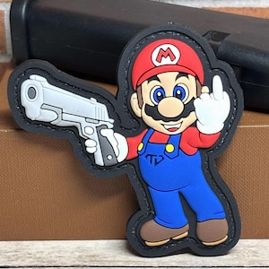 May include: A colorful patch featuring a cartoon character in a red hat and blue overalls, holding a silver handgun and giving the middle finger. The patch has a black border and is set against a neutral background.