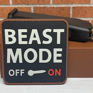 May include: A black patch with brown stitching and the text "BEAST MODE OFF ON" in white and red lettering. The patch has a toggle switch graphic with the word "OFF" to the left and "ON" to the right.
